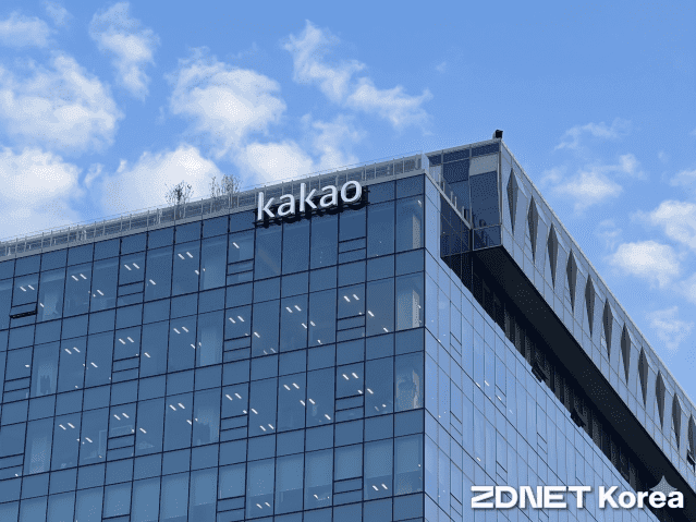 맑은 하늘 아래 'kakao' 사인이 걸린 유리 외벽 사옥 상층부 전경