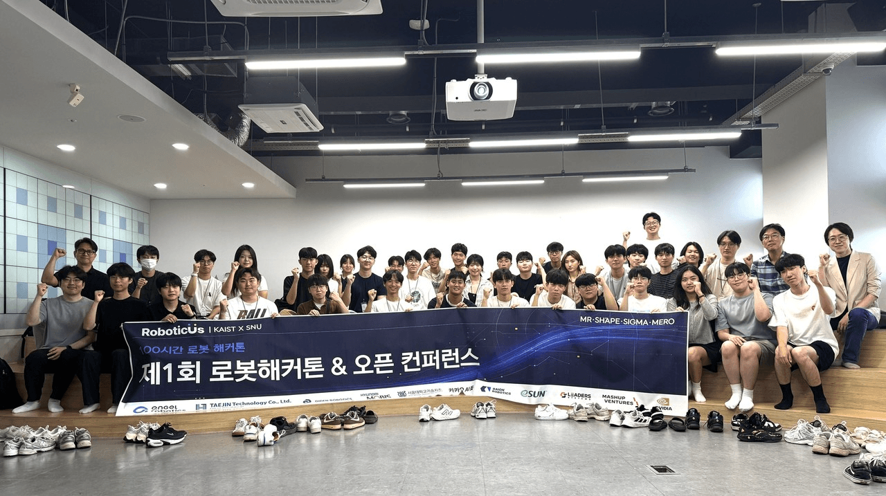 '제1회 로봇해커톤 & 오픈 컨퍼런스' 현수막을 들고 단체 기념촬영 중인 KAIST·서울대 참가 학생들과 운영진, 앞줄 바닥에는 벗어둔 신발이 줄지어 놓여 있다