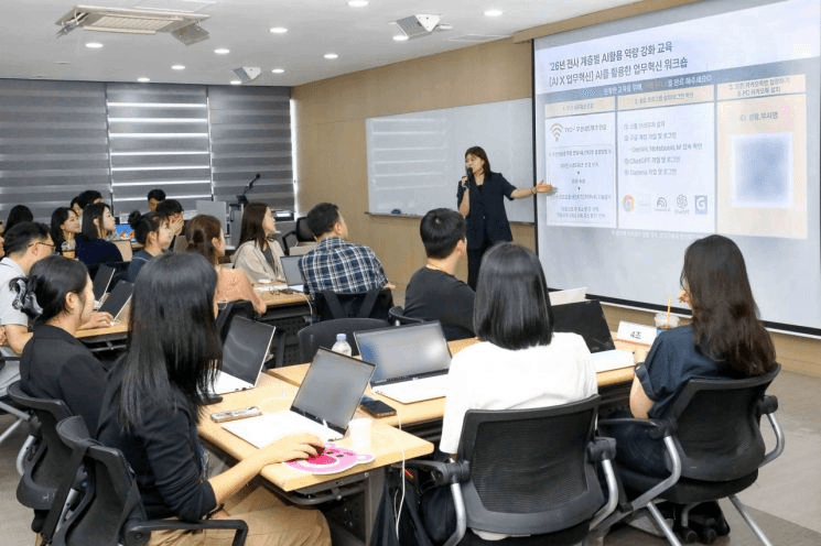 제주항공 임직원 대상 AI 활용 역량 강화 교육 현장. 강사가 'AI 업무혁신 툴을 활용한 업무혁신 워크숍' 슬라이드를 설명하고 수강자들이 노트북으로 실습하고 있다