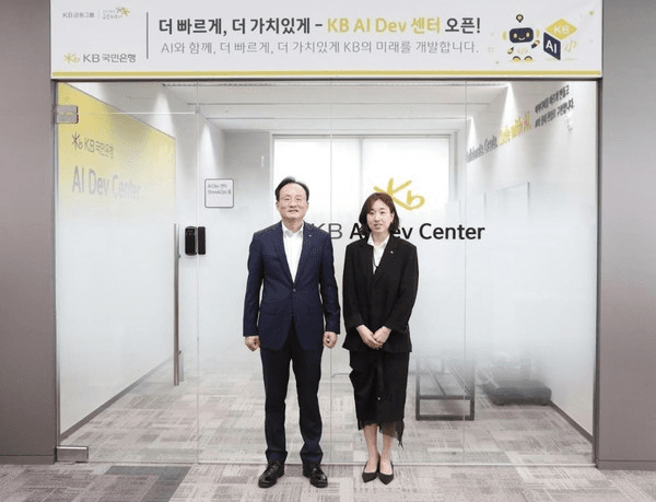 KB국민은행 AI Dev 센터 개소 현장. 'KB AI Dev 센터 오픈' 현수막 아래 관계자 두 명이 서 있다