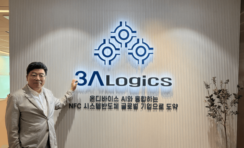 쓰리에이로직스 사무실 로비의 회사 로고 사인월 앞에 선 대표 사진