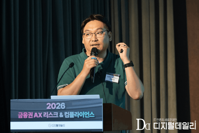 FRC 2026 무대에서 마이크를 들고 발표 중인 김용준 시메이션 대표. 뒤편 연단 화면에 '2026 금융권 AX 리스크 & 컴플라이언스' 문구가 보인다.