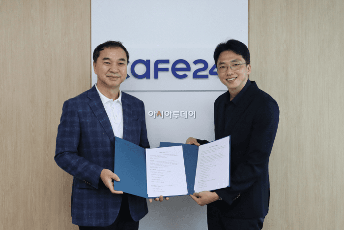 카페24 로고가 붙은 사무실 벽 앞에서 노수열 한국직업전문학교 대표와 김재은 카페24 비즈플랫폼팀 총괄팀장이 AI 인재 양성 산학협력 MOU 협약서를 펼쳐 들고 나란히 서 있다.
