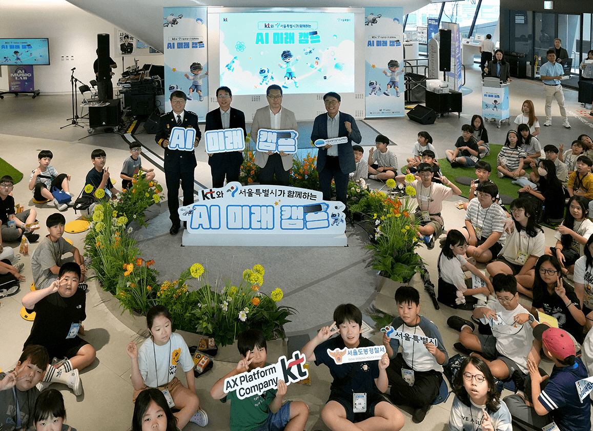 서울로봇인공지능과학관 로비에 초등학생 100여 명이 바닥에 앉아 있고, 앞쪽에 KT·서울시·서울도봉경찰서 관계자들이 'AI 미래 캠프' 손팻말을 들고 선 단체 사진