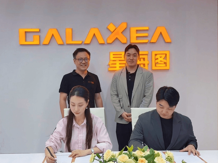 엑스와이지와 중국 갤럭시아 AI 관계자들이 GALAXEA 로고 배경 앞에서 로봇 협력 업무협약서에 서명하는 모습