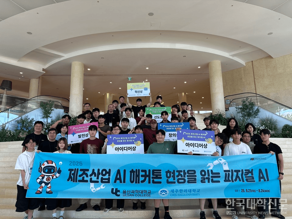 '2026 제조산업 AI 해커톤 현장을 읽는 피지컬 AI' 현수막을 앞세우고 계단에 모여 선 수십 명의 참가자 단체 사진. 뒤쪽 참가자들이 아이디어상·혁신상 등 수상 팻말을 들고 있다