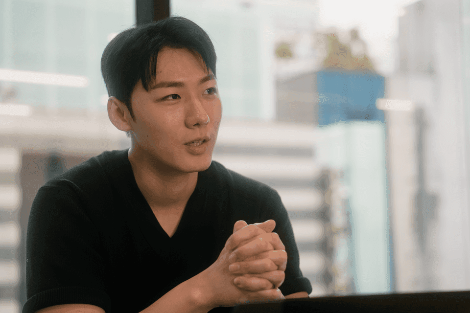 셀렉트스타 김민우 리드가 사무실에서 두 손을 맞잡고 인터뷰에 답하는 모습