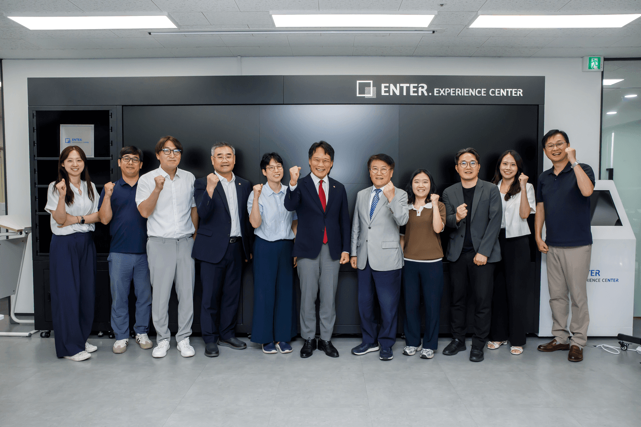 위즈코어 성수생각공장 ENTER 익스피리언스 센터에서 이상훈 한국산업단지공단 이사장 등 참석자 11명이 나란히 서서 기념 촬영을 하고 있다