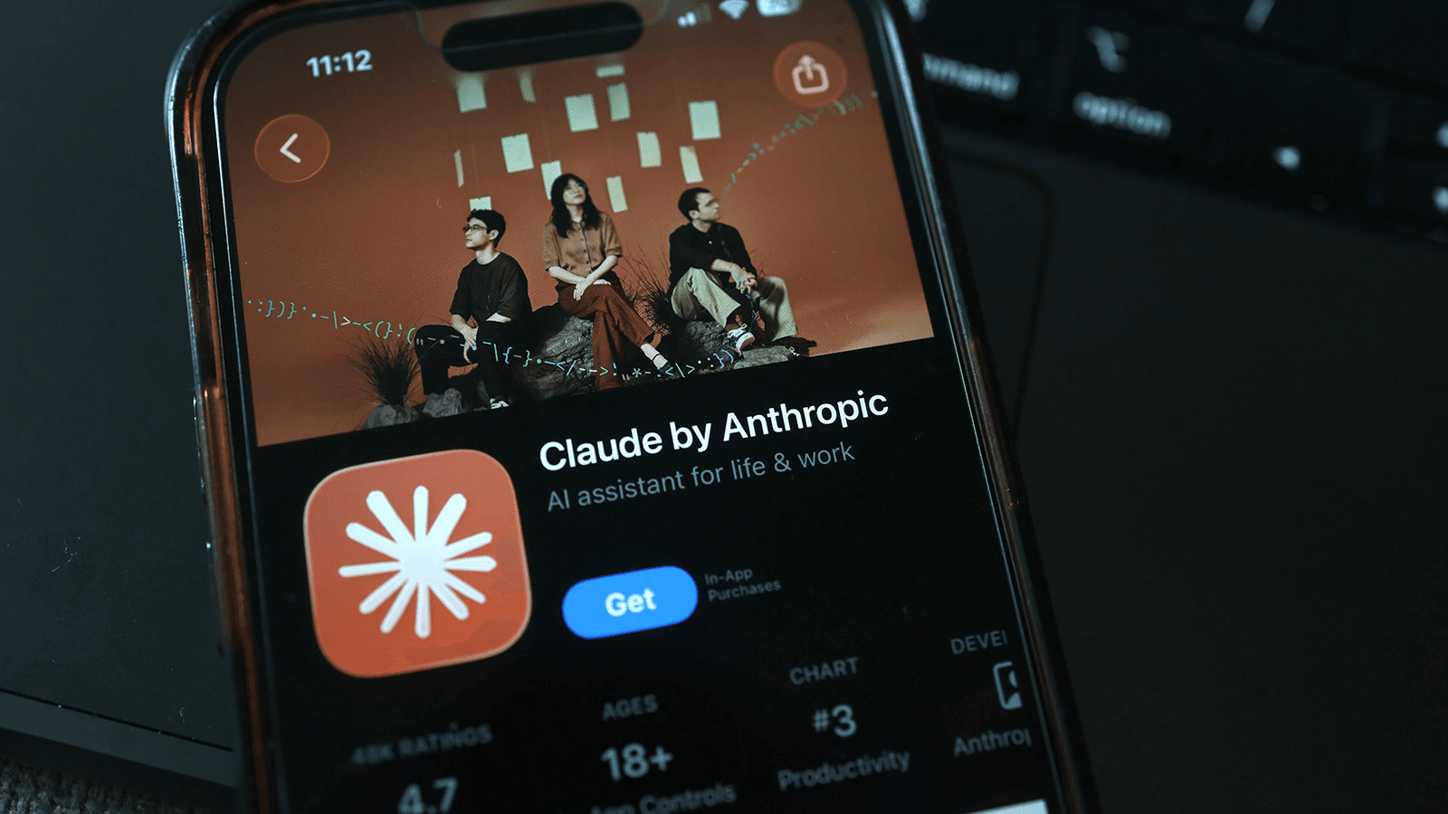 어두운 책상 위 스마트폰 화면에 떠 있는 앱스토어의 Claude by Anthropic 설치 페이지
