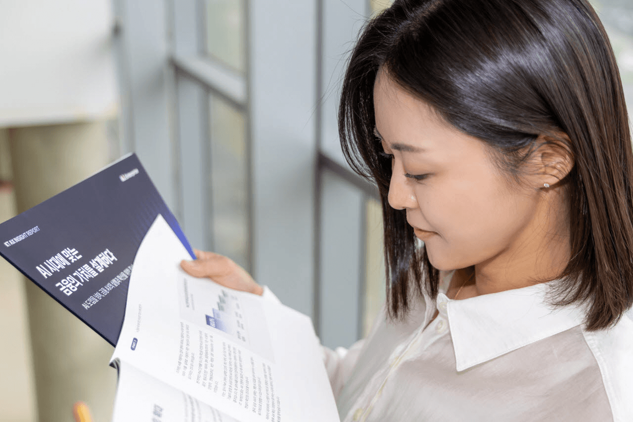 'AI 시대에 맞는 금융의 기준을 설계하다'라는 제목의 KT AX 인사이트 리포트를 펼쳐 보는 모습