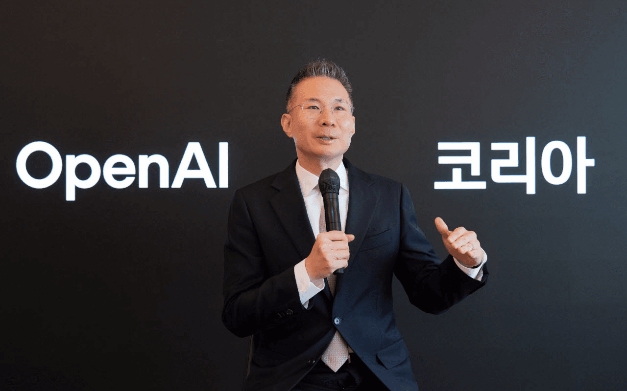 'OpenAI 코리아' 로고가 걸린 검은 배경 앞에서 마이크를 들고 발언하는 오픈AI코리아 김경훈 총괄 대표