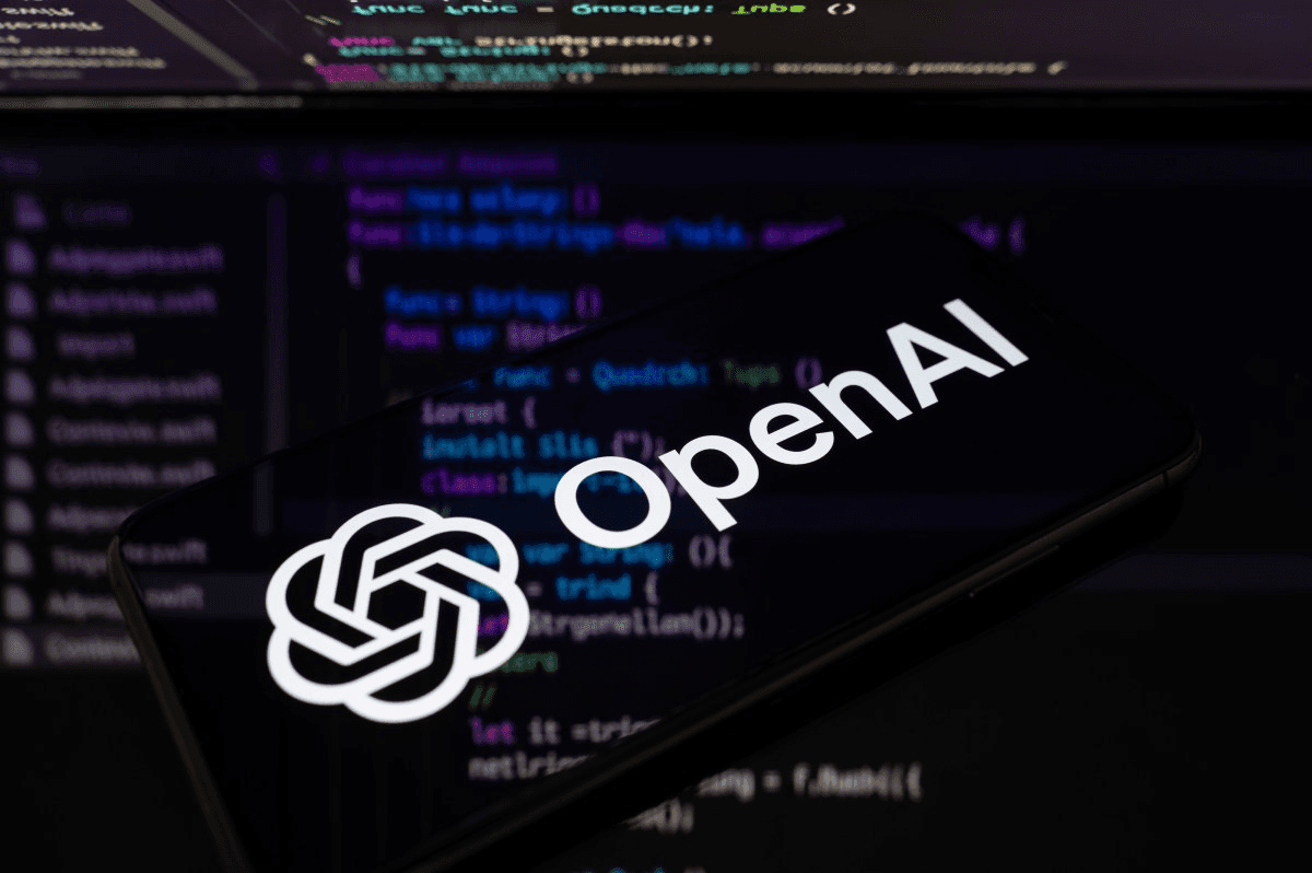 코드 화면을 배경으로 OpenAI 로고가 표시된 스마트폰