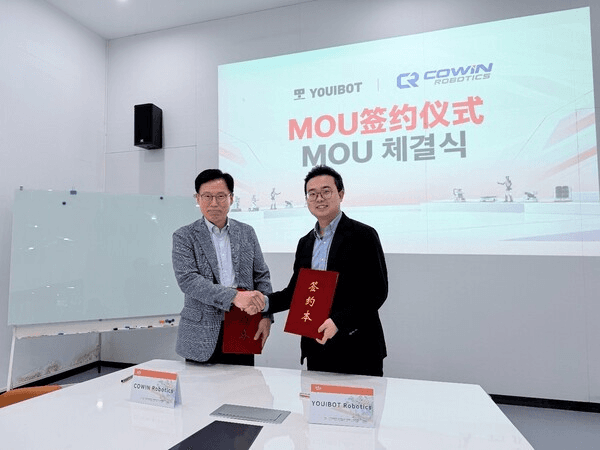 코윈로보틱스와 유아이봇 관계자가 MOU 체결식에서 협약서를 들고 악수하는 모습